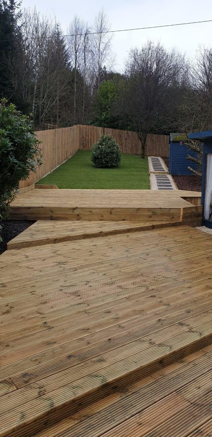 Two-level timber deck, lawn and close-board fence beside the same summerhouse