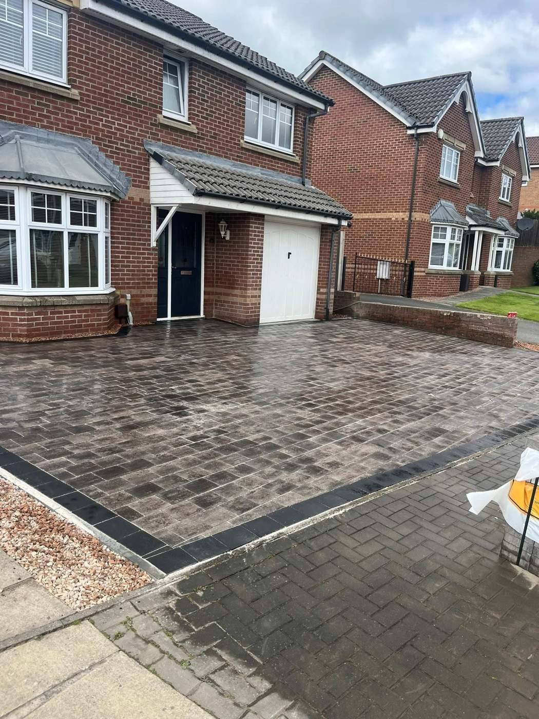 Large grey block-paved driveway at the same brick house