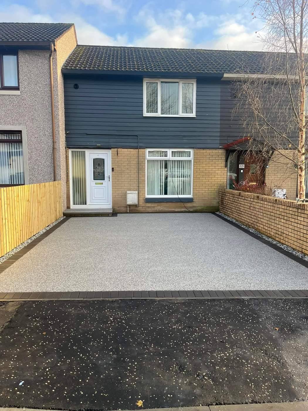 Silver resin driveway in front of a dark-clad house