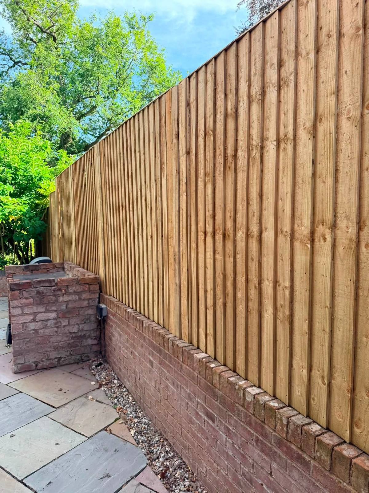 New pale feather-edge fence on the same brick wall