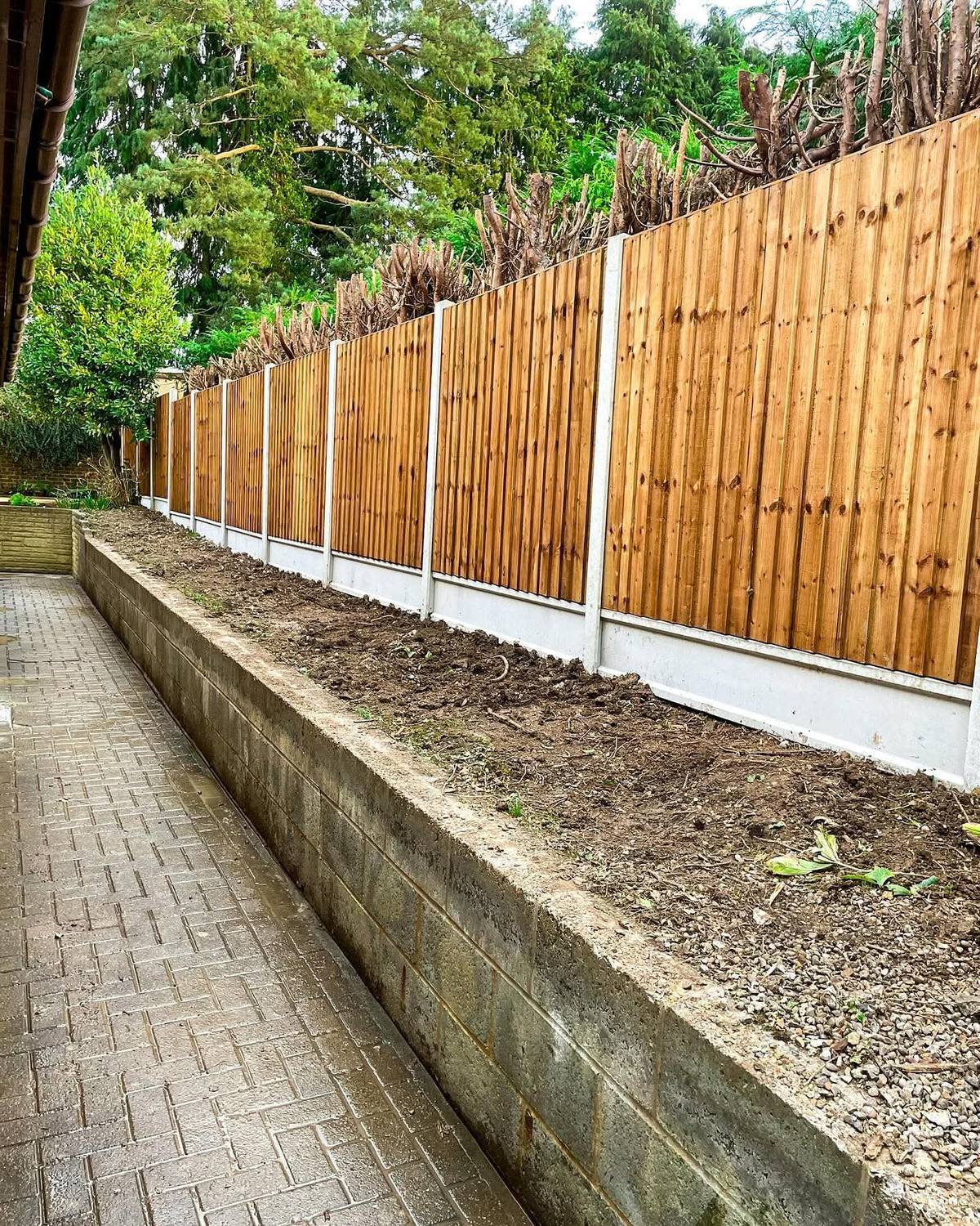 New timber fence on concrete posts above the same wall