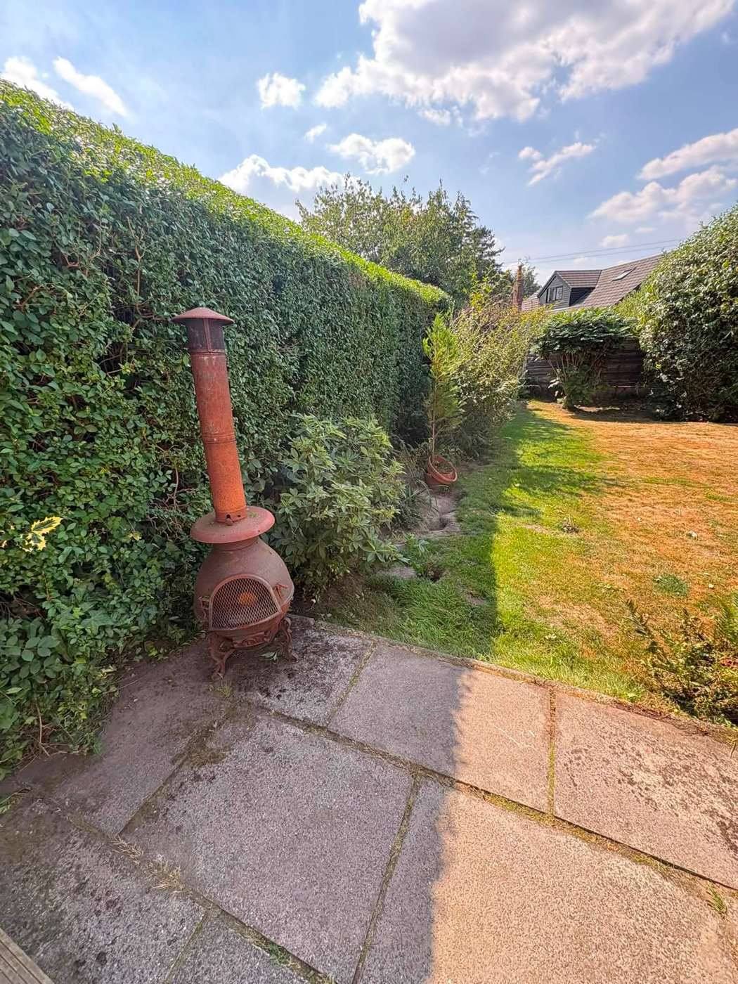 The hedge cut lower behind the same chiminea and patio