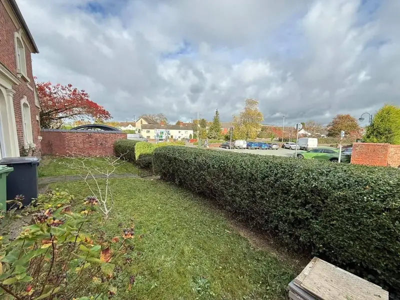 The same hedge trimmed lower, with the houses and car park visible again