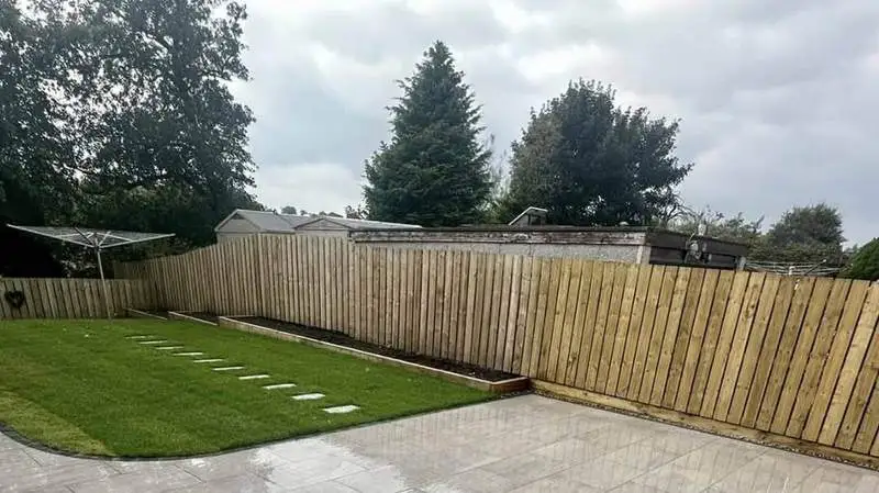 Closeboard fence, shaped lawn with stepping stones and a porcelain patio in a finished Swindon garden
