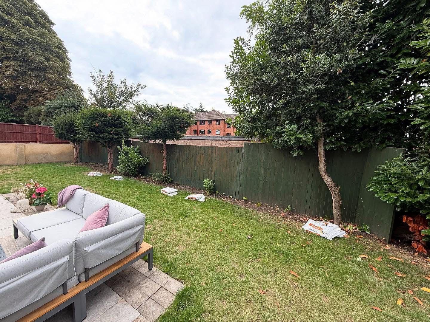 Green closeboard fence along a lawn