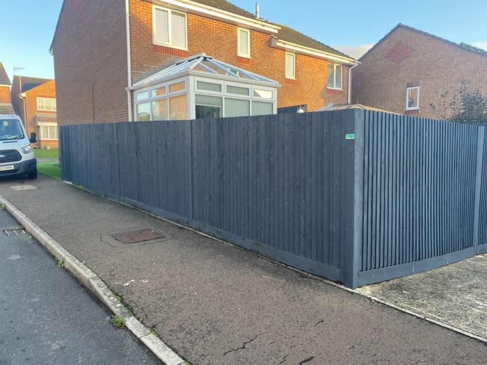 New dark grey vertical-board fence along the same driveway