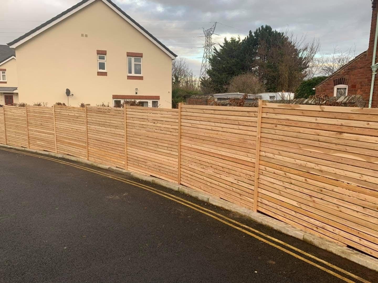 New horizontal slat fence along the same road