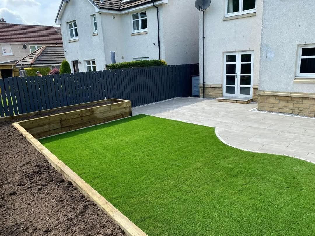 Artificial grass, light patio and a timber planter by the same fence