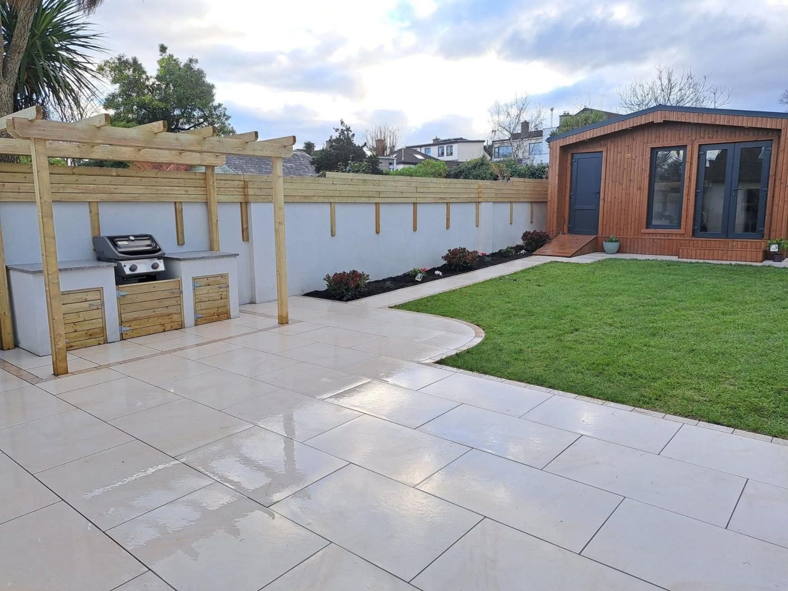 Porcelain patio with an outdoor kitchen, curved lawn and summerhouse