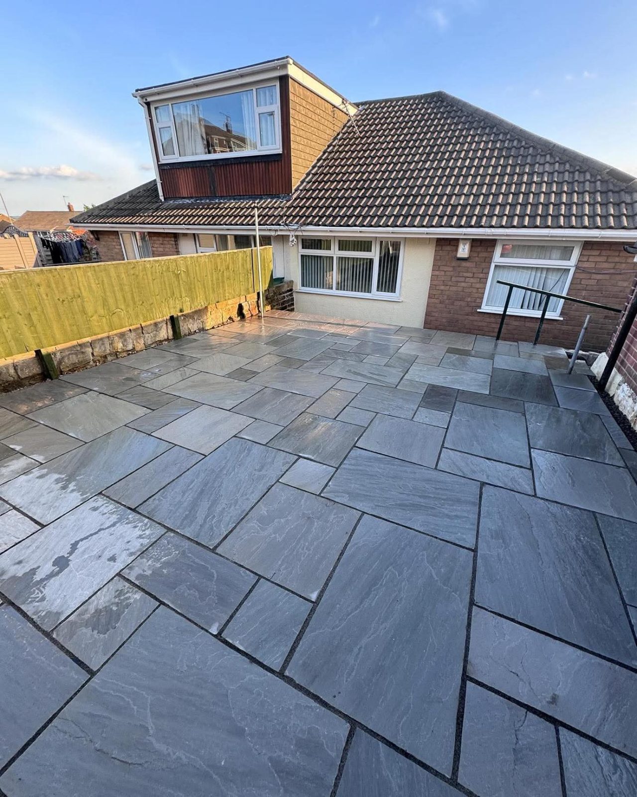 Grey porcelain patio behind a dormer bungalow