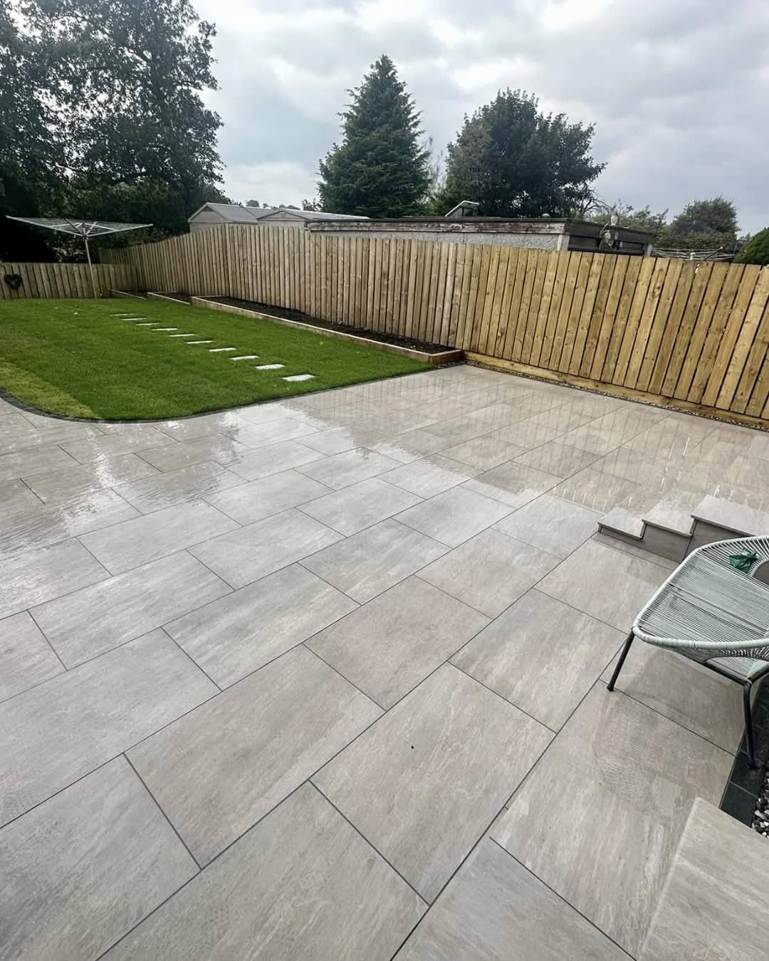 New light porcelain patio beside a lawn and timber fence