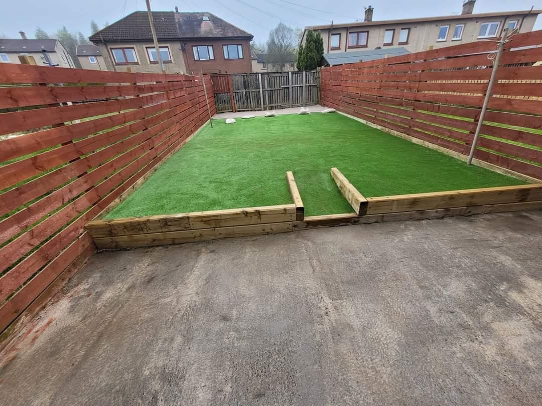 Artificial grass with a timber edge between the same fence panels